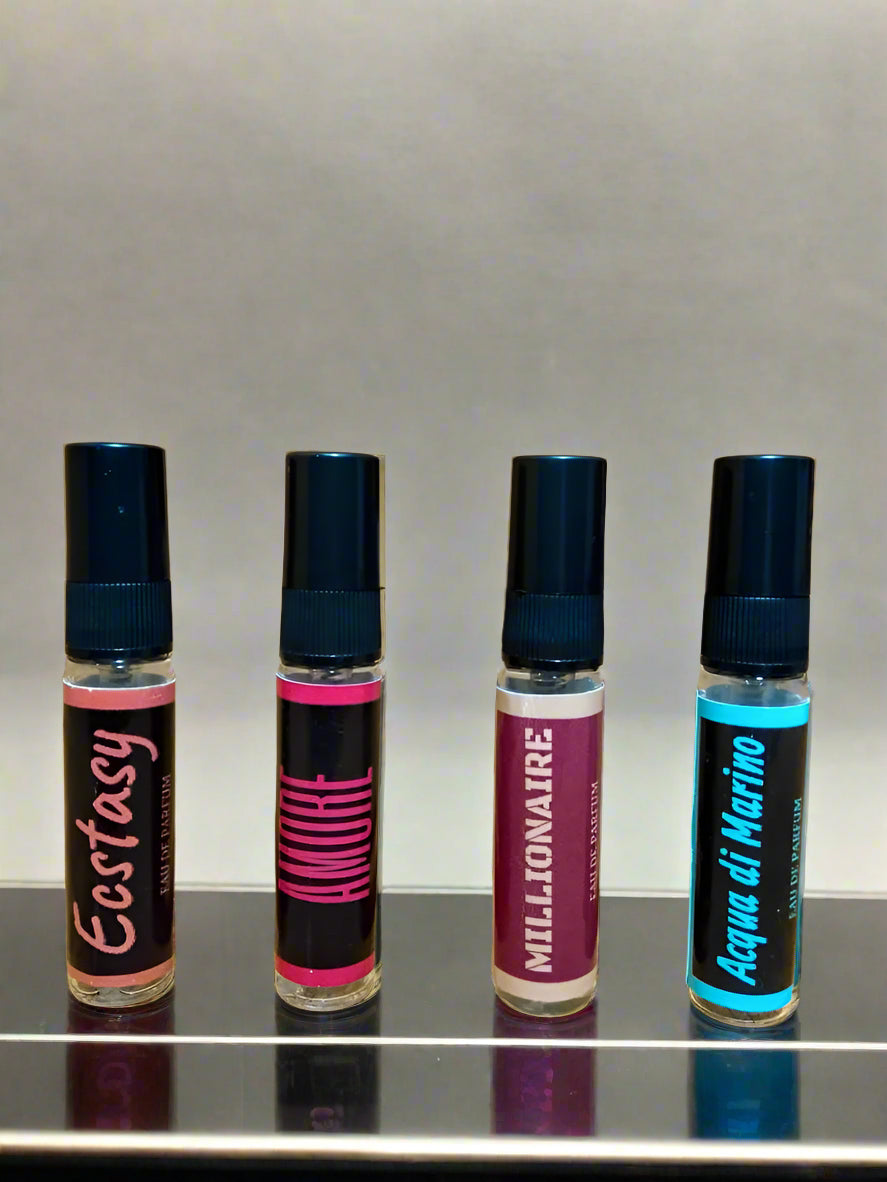 Four small bottles of different scents on a wooden surface.